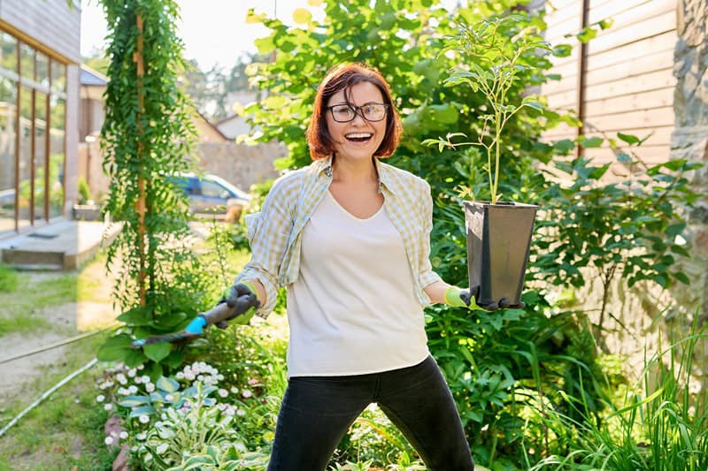 smiling woman with flowerpot with peony plant and 2023 11 27 04 58 39 utc